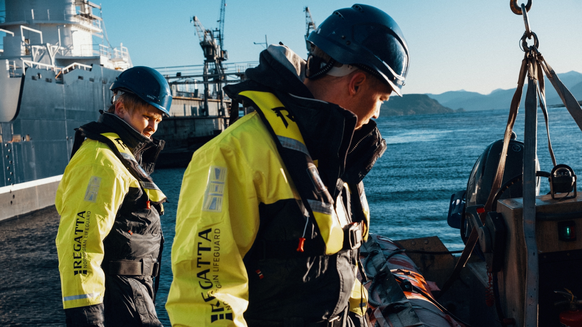 To personer på verft, iført flytedrakt og oppblåsbar redningsvest fra Regatta